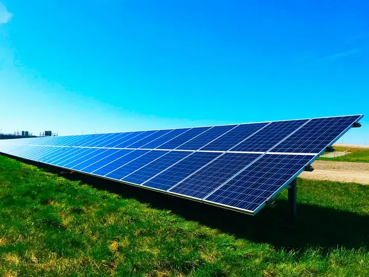 Fileira de placas solares em área rural com céu azul