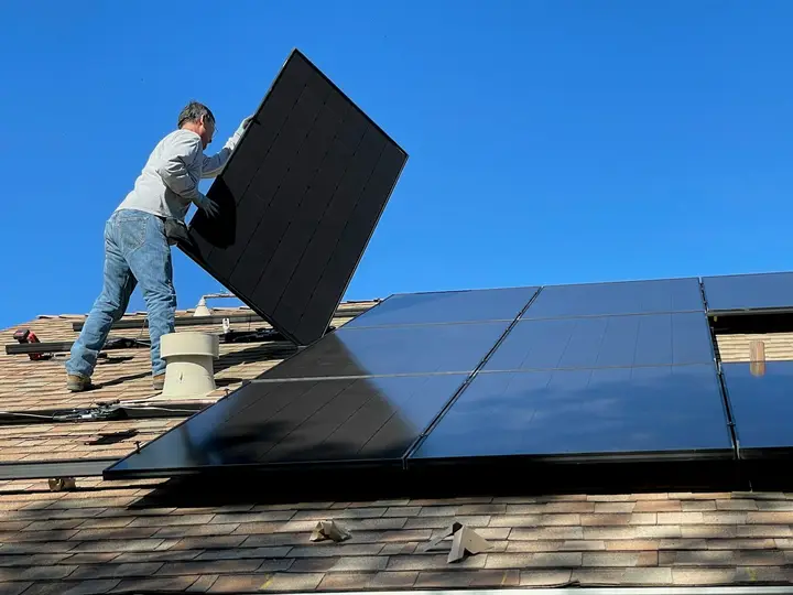 Instalador posicionando placa solar em um telhado